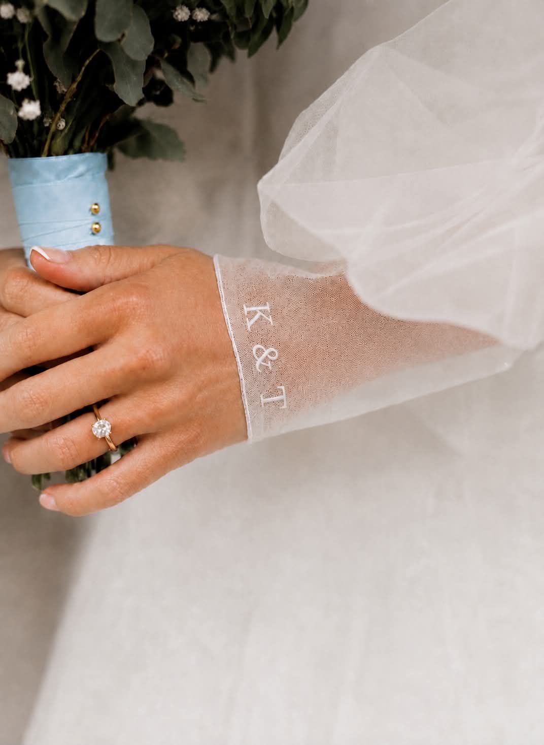Personalised wedding dress embroidery featuring the initials K & T and wedding date embroidered in pale ivory thread on ivory bridal fabric.